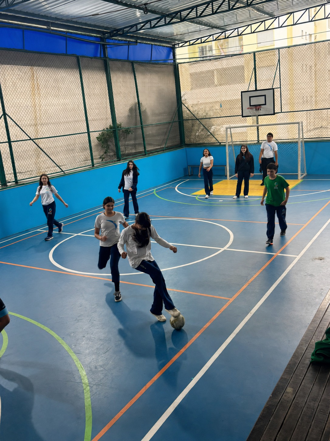 Alunos jogando futsal na quadra coberta