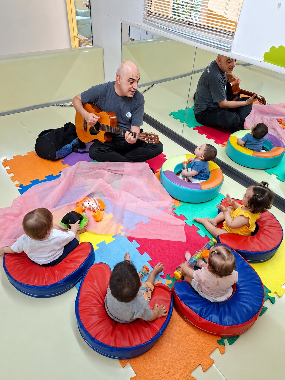 Professor com violão em roda de musicalização com bebês