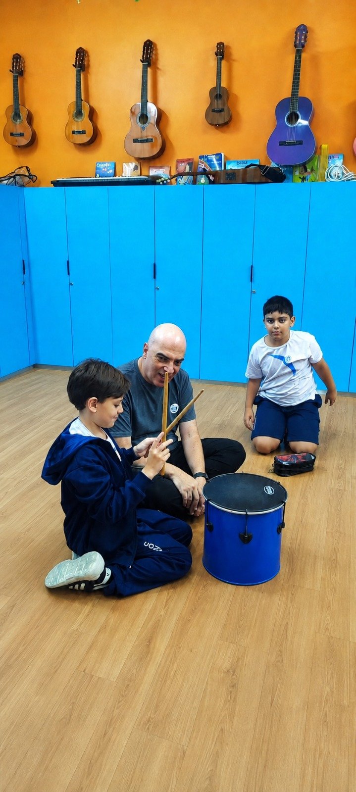 Aluno tocando tambor com professor de musicalização
