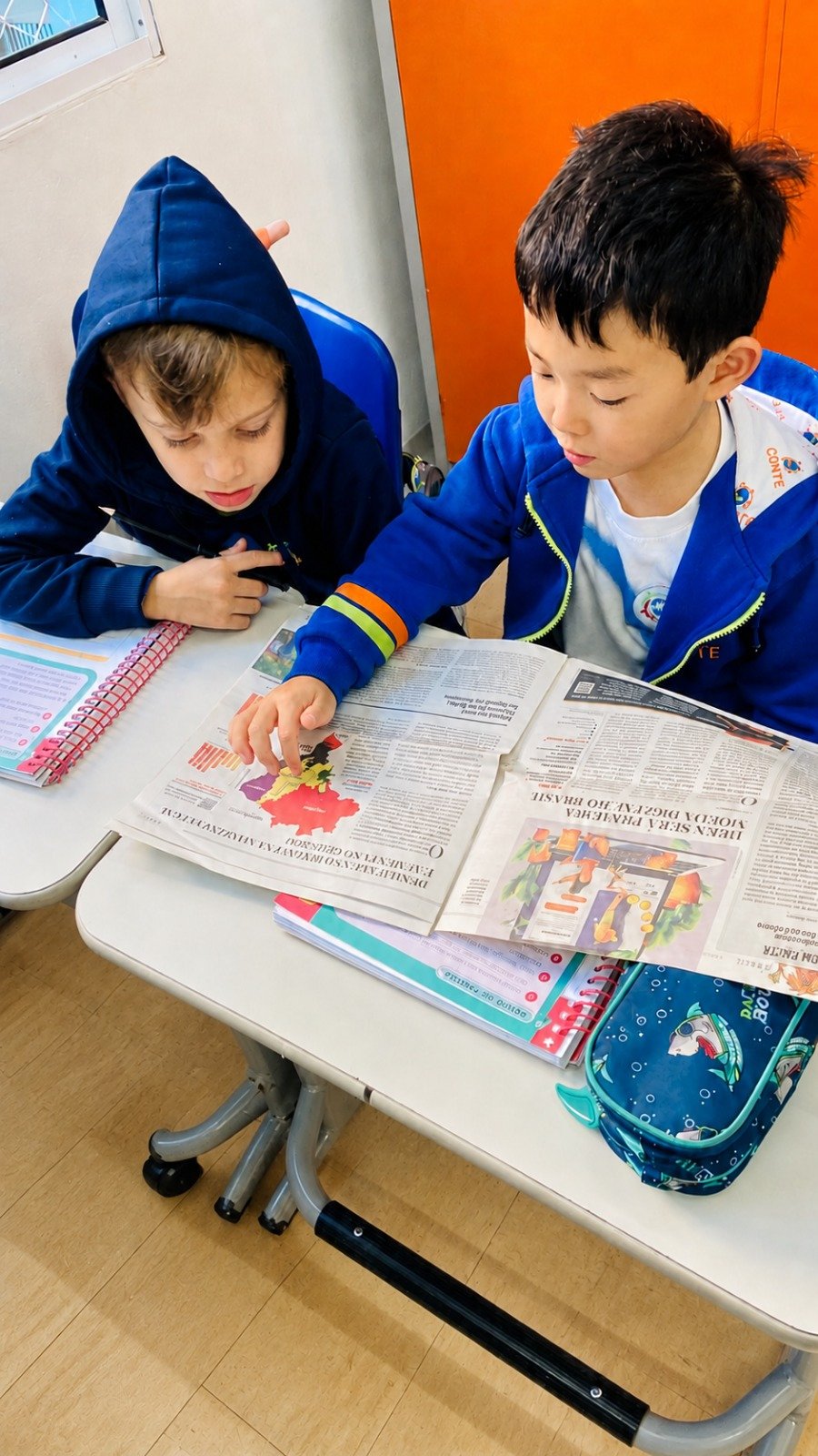 Alunos analisando mapa em jornal na atividade de pesquisa e leitura