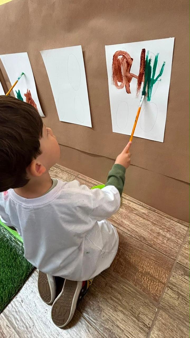 Criança pintando com tinta na atividade de Arte